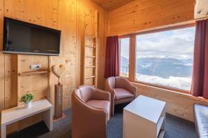 ツァムスにあるVenet Gipfelhotelの椅子2脚、テレビ、窓が備わる客室です。