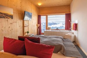 - une chambre avec une grande fenêtre et un lit avec des oreillers rouges dans l'établissement Venet Gipfelhütte, à Zams
