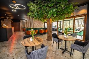 a restaurant with two tables and chairs and a tree at Hotel Sailor Łeba in Łeba