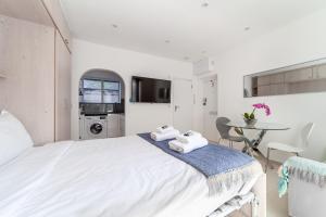 a white bedroom with a bed and a table at Bright Studio Flat in the Heart of Marylebone in London