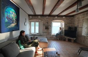 two people sitting on couches in a living room at Apartment Dyonis Perast in Perast