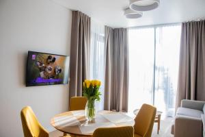 uma mesa de jantar com cadeiras amarelas e um vaso de flores em Parko Aveniu Apartamentai em Birstonas