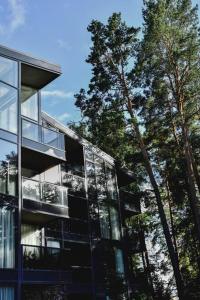 um edifício de vidro com árvores em frente em Parko Aveniu Apartamentai em Birstonas