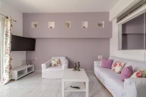 a white living room with a white couch and a tv at Akali Apt Next to the Beach in Milatos