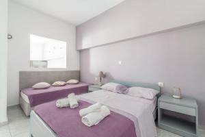 twee bedden in een kamer met paars en wit bij Akali Apt Next to the Beach in Milatos