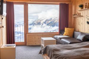 ツァムスにあるVenet Gipfelhotelのベッド1台、山の景色を望む大きな窓が備わる客室です。