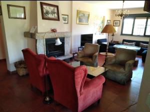 a living room with red chairs and a fireplace at La Cirujana de Gredos in San Esteban del Valle