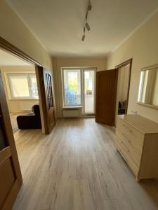 an empty living room with wooden floors and windows at Ruses. One Bedroom Apartment in Rīga