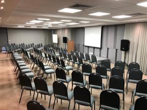an empty room with chairs and a screen at Diaudi Hotel in São José