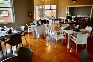 uma sala de jantar com mesas brancas e cadeiras brancas em The Mole Guesthouse em Swakopmund