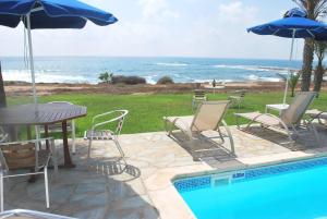 uma piscina com cadeiras e guarda-sóis e o oceano em Sea Front Villa With Private Heated Pool, Quiet area Paphos 322 em Kissonerga