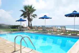 een zwembad met stoelen en parasols en de oceaan bij Sea Front Villa With Private Heated Pool, Quiet area Paphos 322 in Kissonerga