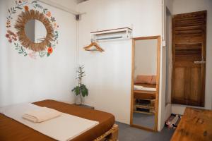 um pequeno quarto com uma cama e um espelho em Sacred Lotus - Vegan Café X Hostel em Phnom Penh