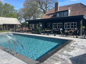 a swimming pool in front of a house at Camping de Vinkenkamp in Lieren