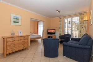 ein Wohnzimmer mit einem Sofa, Stühlen und einem TV in der Unterkunft Dünenschloss Dünenschloss 2-09 in Kühlungsborn