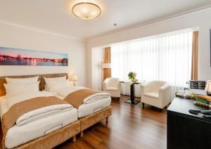 ein weißes Schlafzimmer mit einem großen Bett und einem Schreibtisch in der Unterkunft Hotel von Stephan in Westerland
