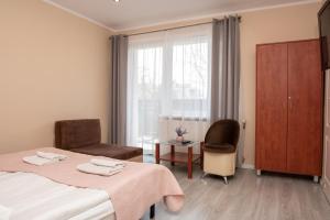 um quarto com uma cama, uma cadeira e uma janela em Willa Maja em Ciechocinek