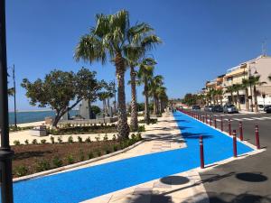 une grande piscine bleue à côté d'une rue bordée de palmiers dans l'établissement Casa Vacanza Rosa, à Pozzallo