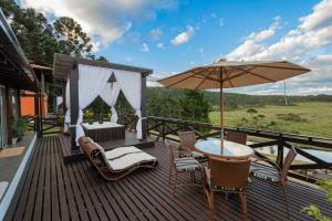 a wooden deck with a table and an umbrella at Sierra Garden Houses in Bom Jardim da Serra