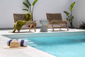 a swimming pool with two chairs and a hat next to it at Assos Aqua Apartment in Heraklio Town