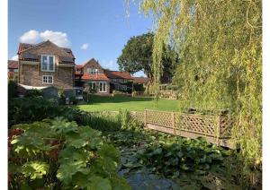 un puente sobre un estanque frente a una casa en Acorn Attic, a modern, new first floor garden annex, en Great Ouseburn