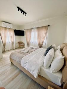ein Schlafzimmer mit einem großen Bett mit weißer Bettwäsche und Kissen in der Unterkunft Olea White in Skiathos-Stadt
