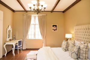 a bedroom with a bed and a table and a window at Remhoogte Mountain Lodge in Jacksonstuin