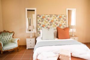 a bedroom with a large bed and a chair at Remhoogte Mountain Lodge in Jacksonstuin