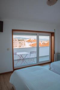 a bedroom with a large window with a view at Arca Nova Guest House & Hostel Caminha in Caminha