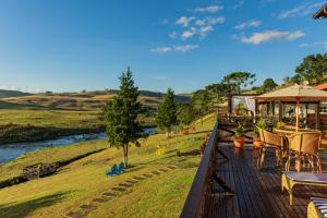 a deck with tables and chairs and a river at Sierra Garden Houses in Bom Jardim da Serra