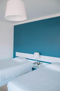 2 letti in una camera con parete blu di Arca Nova Guest House & Hostel Caminha a Caminha
