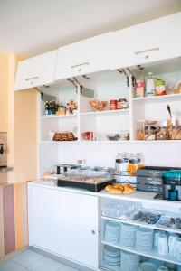 una cocina con armarios blancos y platos en estanterías en Arca Nova Guest House & Hostel Caminha, en Caminha