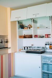 una cocina con armarios blancos y platos en estanterías en Arca Nova Guest House & Hostel Caminha en Caminha