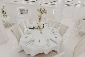 a white room with a long table with white chairs at Svadbeni salon i prenoćište MILANOVIĆ in Nevesinje