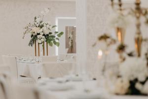 a room with white tables and white chairs and flowers at Svadbeni salon i prenoćište MILANOVIĆ in Nevesinje