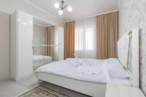 a white bedroom with a large bed and a mirror at Жк Millennium Park, Большие Апартаменты на площади страны in Astana
