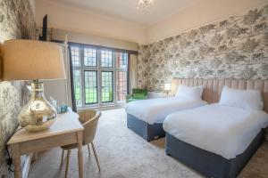 a bedroom with two beds and a table with a lamp at Broome Park Hotel in Canterbury