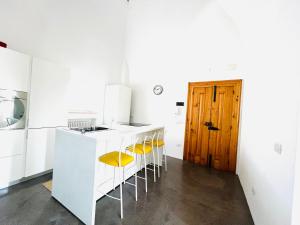uma cozinha com um balcão branco e bancos amarelos em View - Art house Roof top sea view em Polignano a Mare mais 18 fotografias