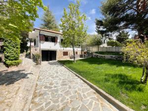 una casa con una pasarela de piedra frente a un patio en La Fontanilla en Estación de El Espinar, en Segovia