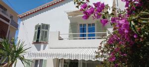 a white building with a blue window and purple flowers at Dana Paradise House in Nice