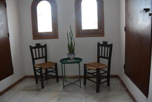 two chairs and a table in a room with two windows at Purísima Vivienda Turística in Córdoba