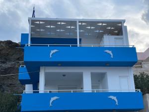 a blue building with two dolphins on it at Mediterranean Dolphin Guest House in Paránimfoi