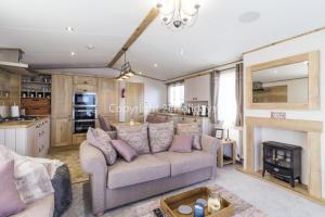 a living room with a couch and a fireplace at Stunning 8 Berth Caravan With Sea Views Decking At Hopton-on-sea Ref 80004h in Great Yarmouth