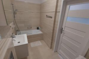y baño con bañera, lavamanos y ducha. en Nowiutki apartament z bezpłatnym parkingiem, en Rumia
