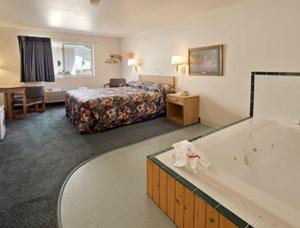 ElyにあるNorthwoods Inn and Suitesのベッドとバスタブ付きのホテルルームです。