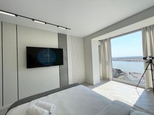 1 dormitorio con 1 cama y TV en la pared en LUX с видом на набережную, en Pavlodar