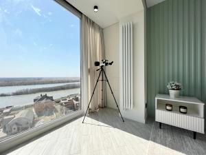 a camera on a tripod in a room with a large window at LUX с видом на набережную in Pavlodar