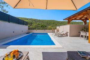 a swimming pool in a backyard with a table and chairs at New! Charming Villa Perina with private heated pool in Tugare