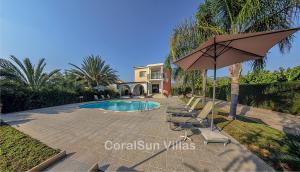 Un patio con sillas y sombrilla y una piscina. en Amazing Pool, Complete Privacy, Amenities and Beach nearby, en Peyia