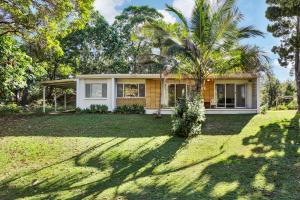 a house with a palm tree in front of a yard at Billa Bungalow - 16 Billa Street in Point Lookout